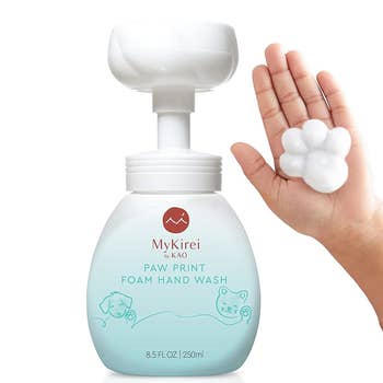 bottle of the soap with model's hand holding paw shaped foam