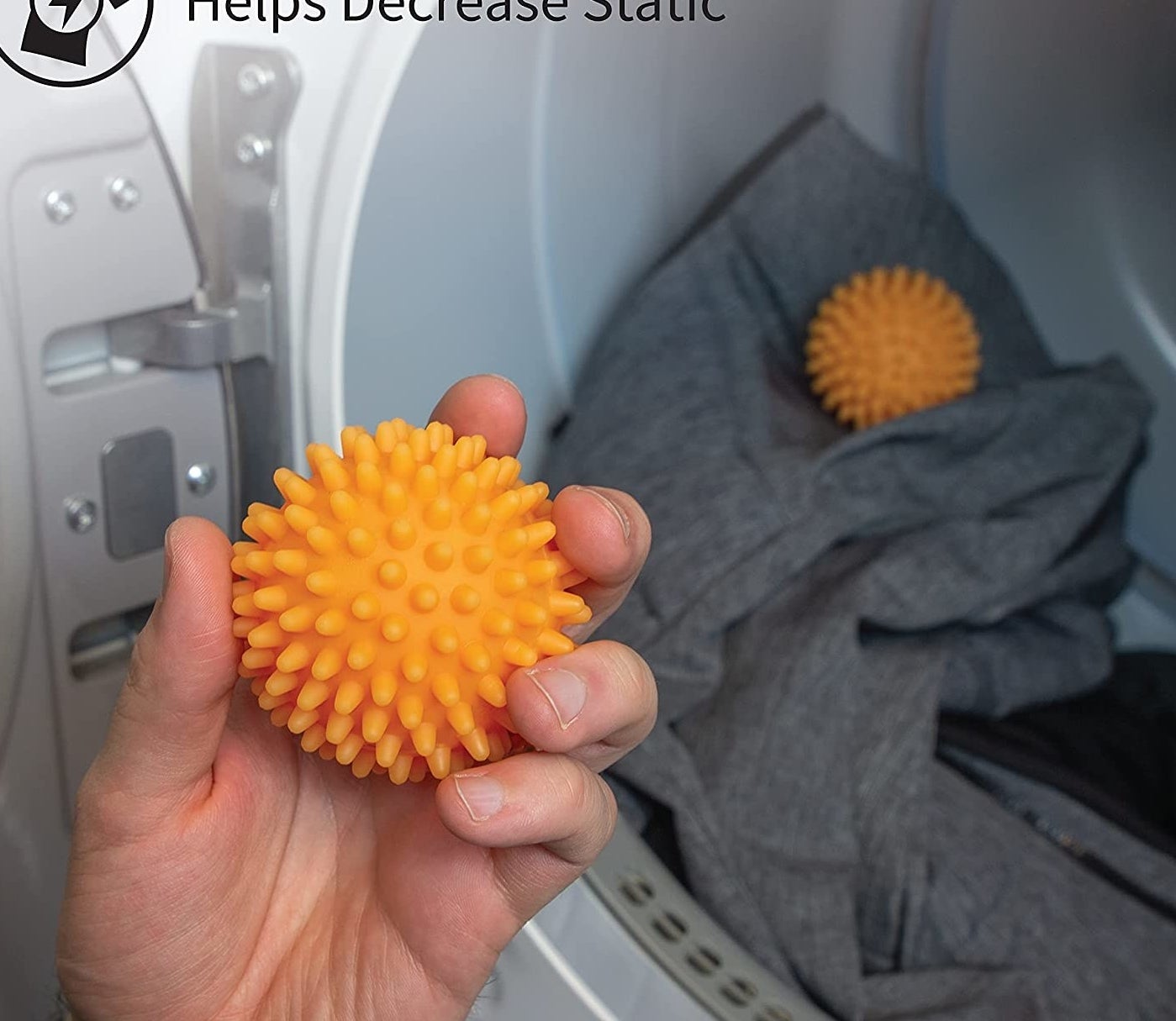 someone holding one of the spiked dryer balls; two others are visible inside