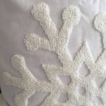 Reviewer close-up showing the embroidered snowflake detail on a white pillow cover