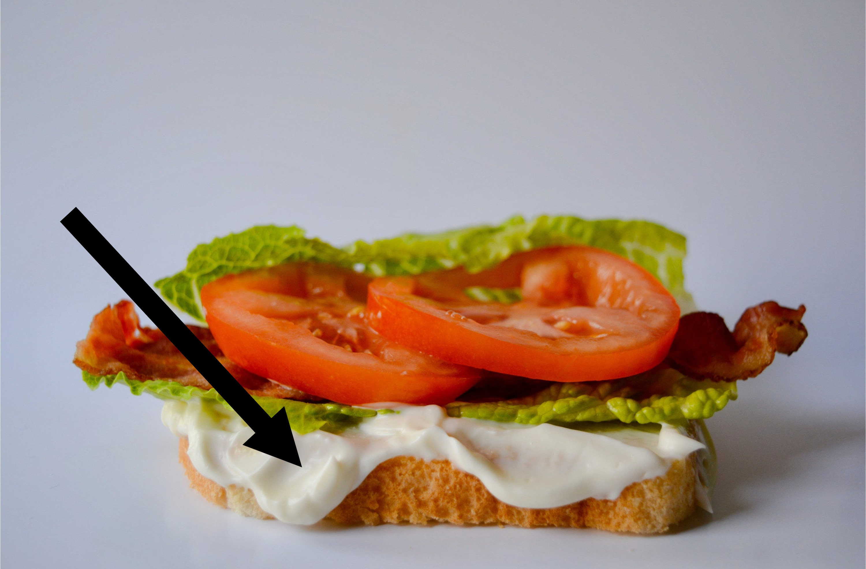 A BLT on bread with mayonnaise.