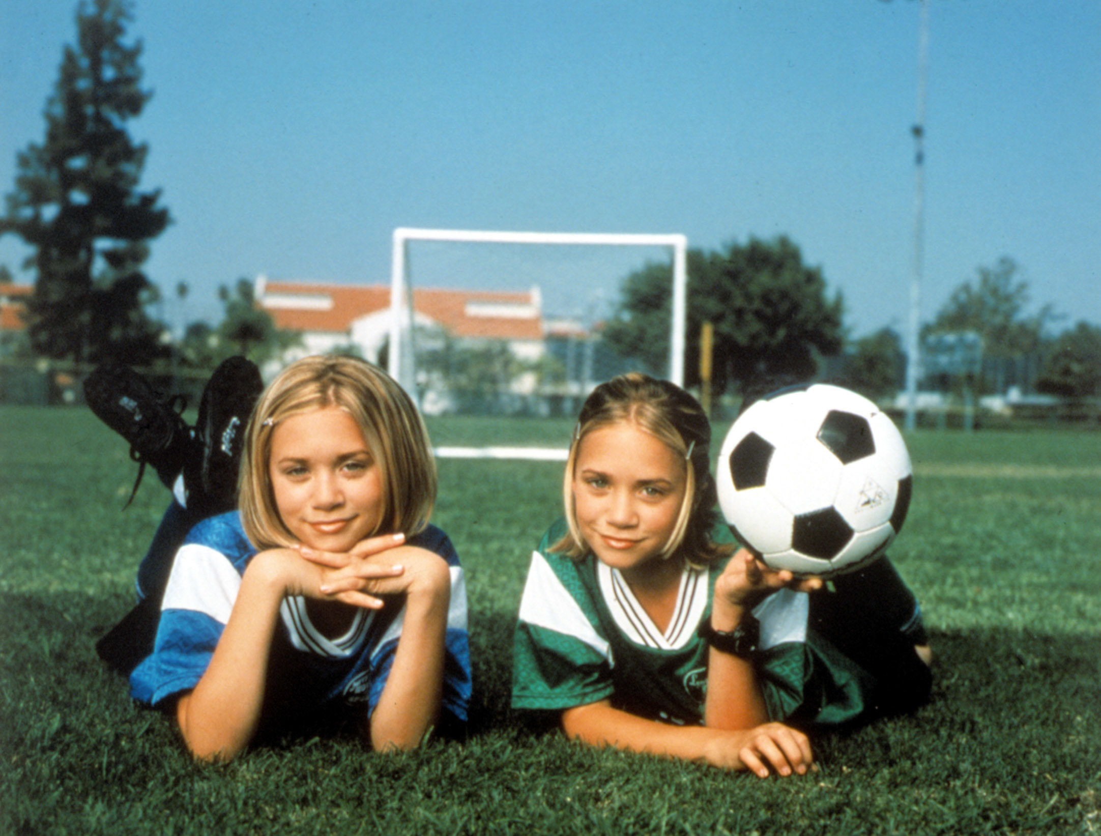 Mary-Kate and Ashley lying on their stomachs on a soccer field as Emma and Sam