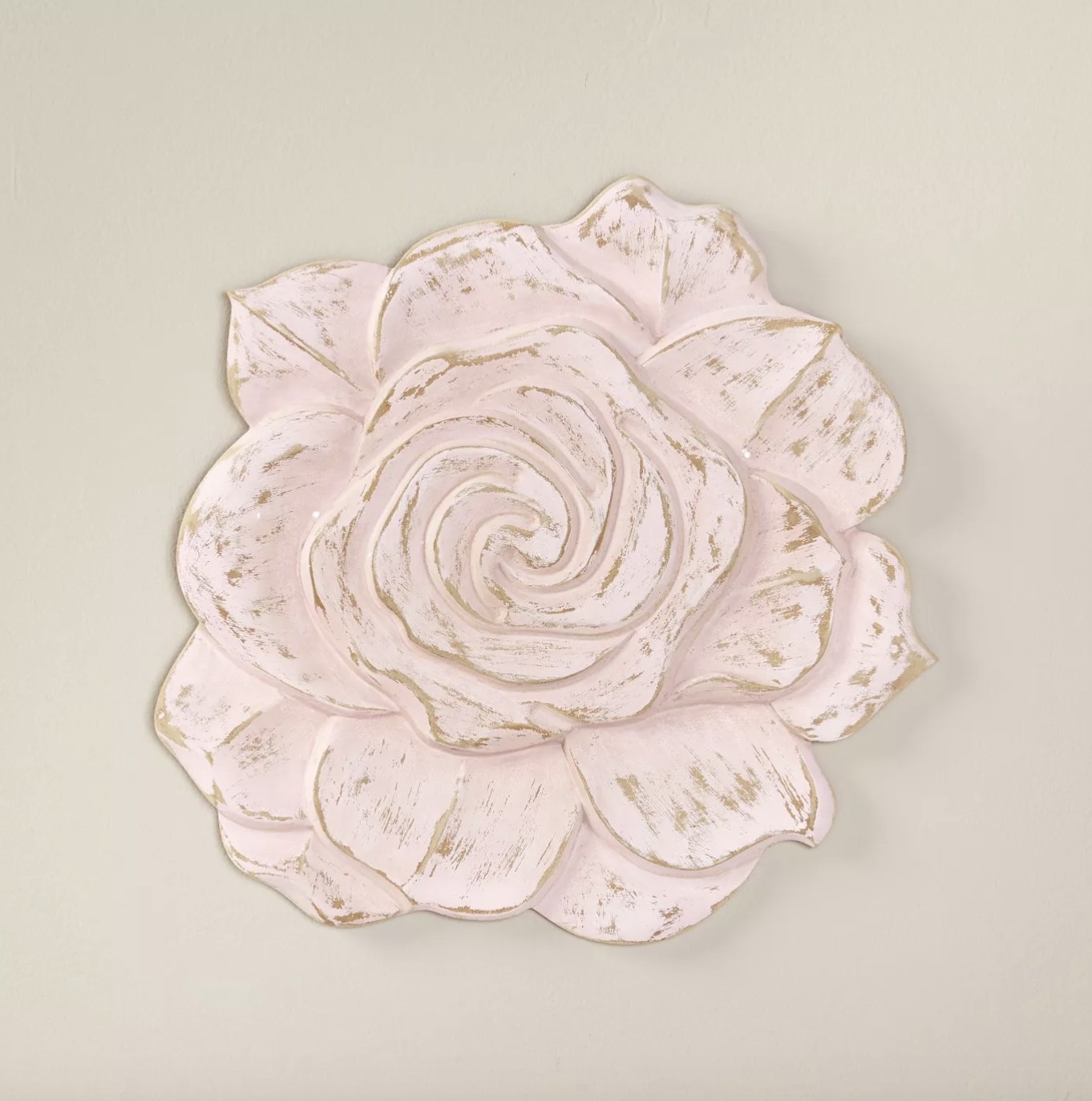 The carved flower has a light pink wash and vintage look on a neutral wall