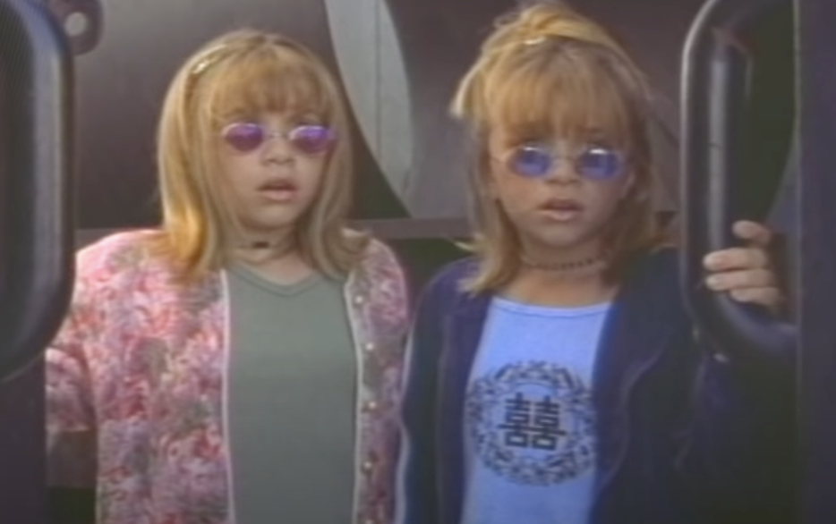Mary-Kate and Ashley opening their mouths wide in surprise as they open a door as Tess and Emily