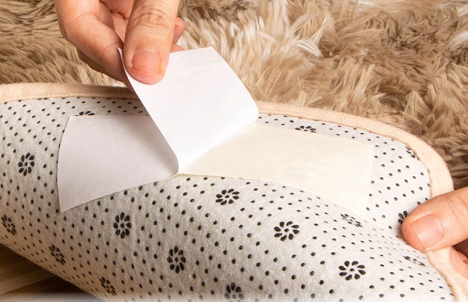 a person peeling the backing off the carpet tape