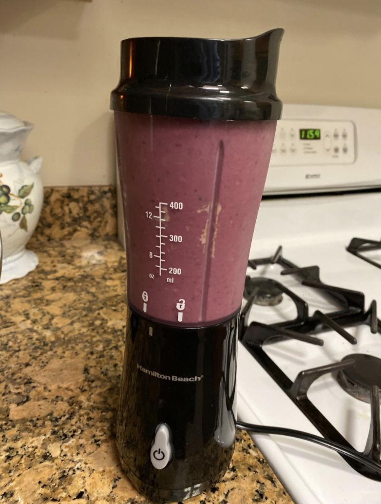 The black blender with a cup of purple smoothie in it