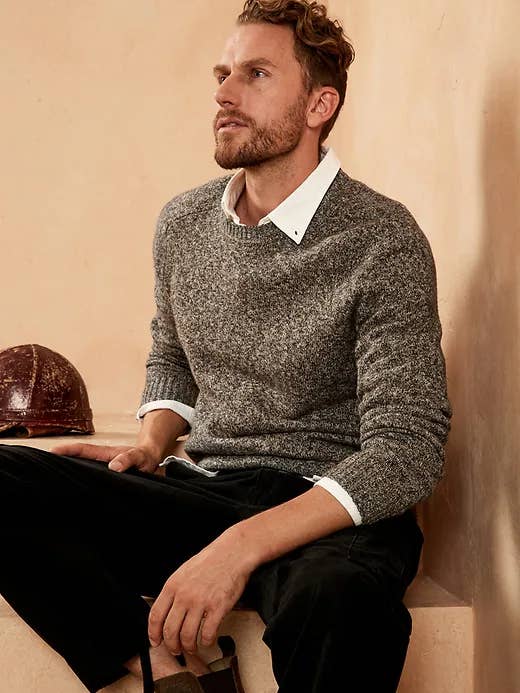 A man wearing the sweater in grey