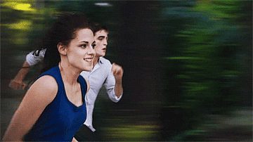 Kristen Stewart and Robert Pattinson run through the forest