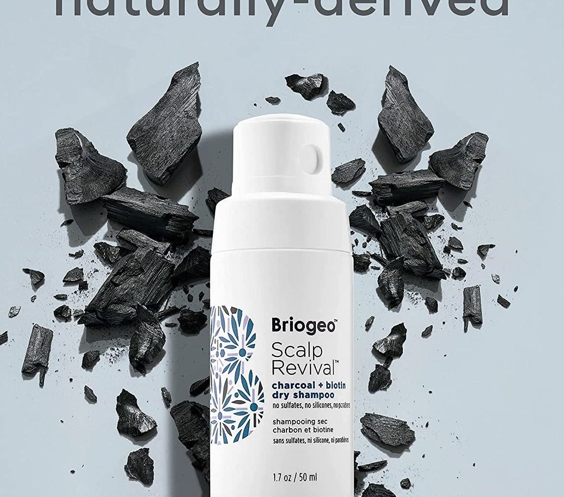 the bottle of dry shampoo against pieces of charcoal