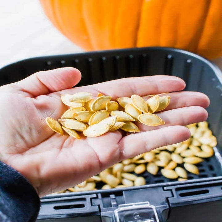 A hand filled with pumpkin seeds.
