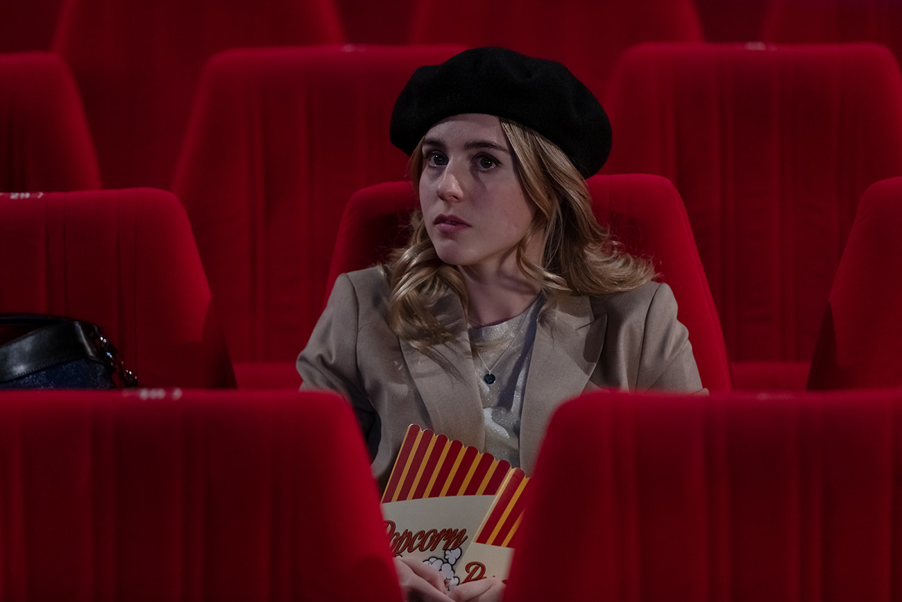 A woman sitting in a theater with velvet seats