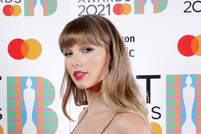 Taylor Swift poses for a picture with her hand on her hip on the red carpet