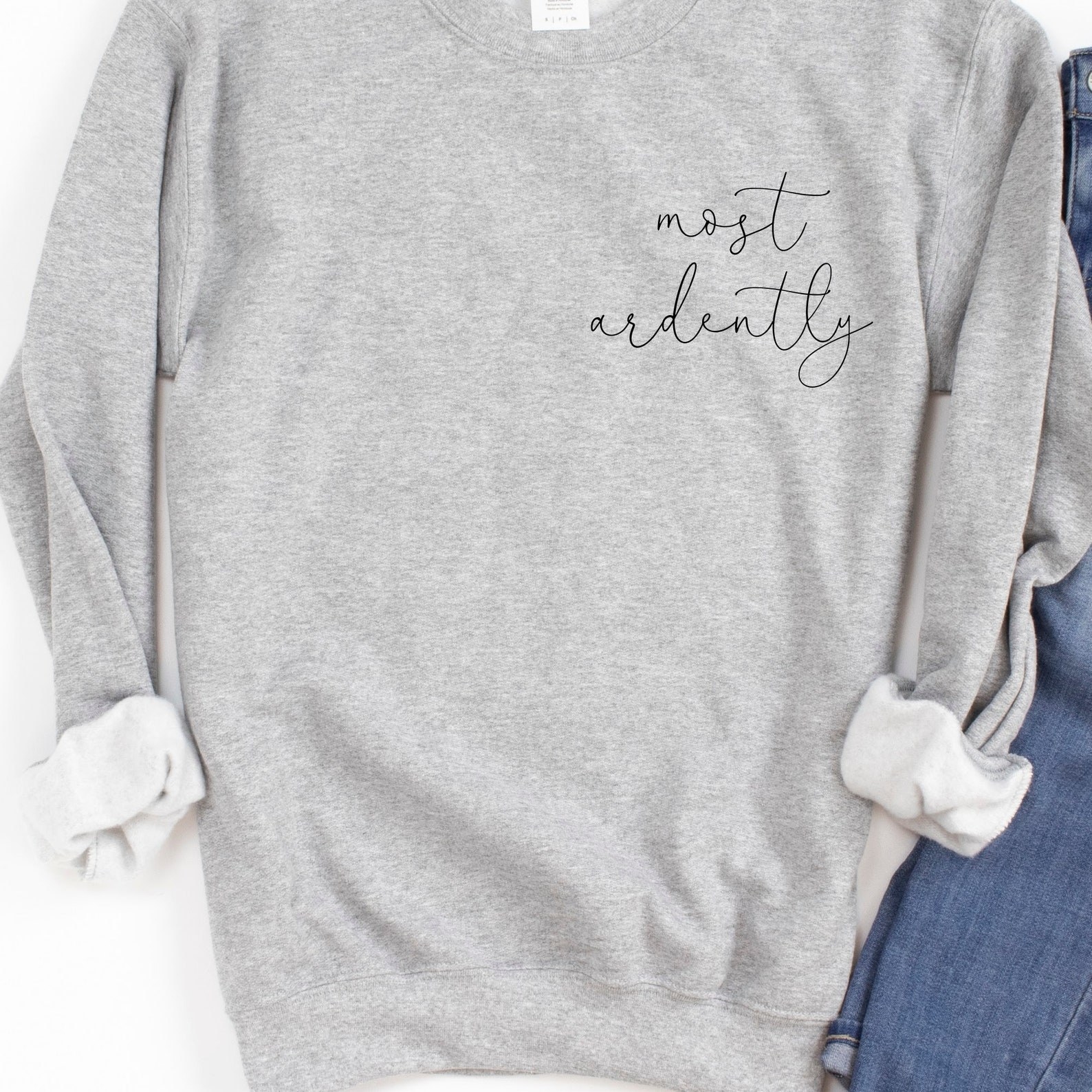 The grey sweatshirt with cursive text &quot;most ardently&quot; on one side