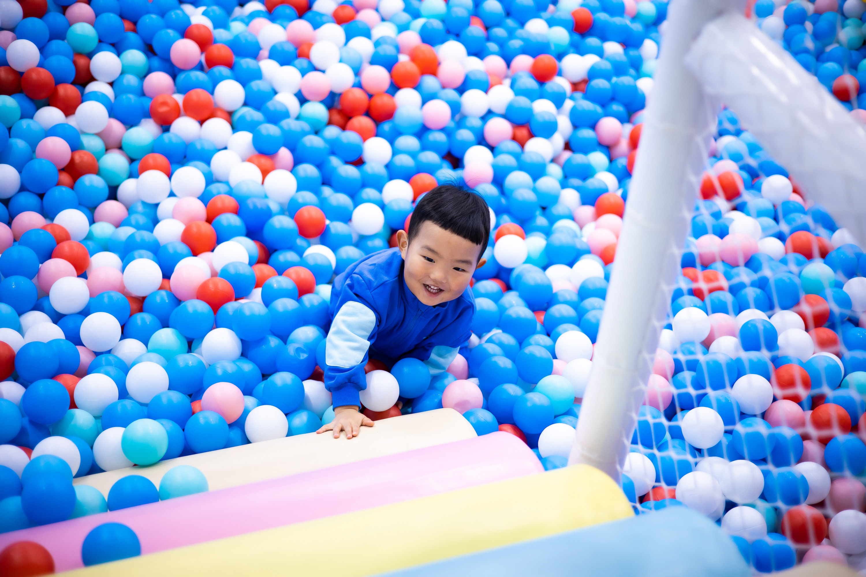 Little boy playing in a ball pit