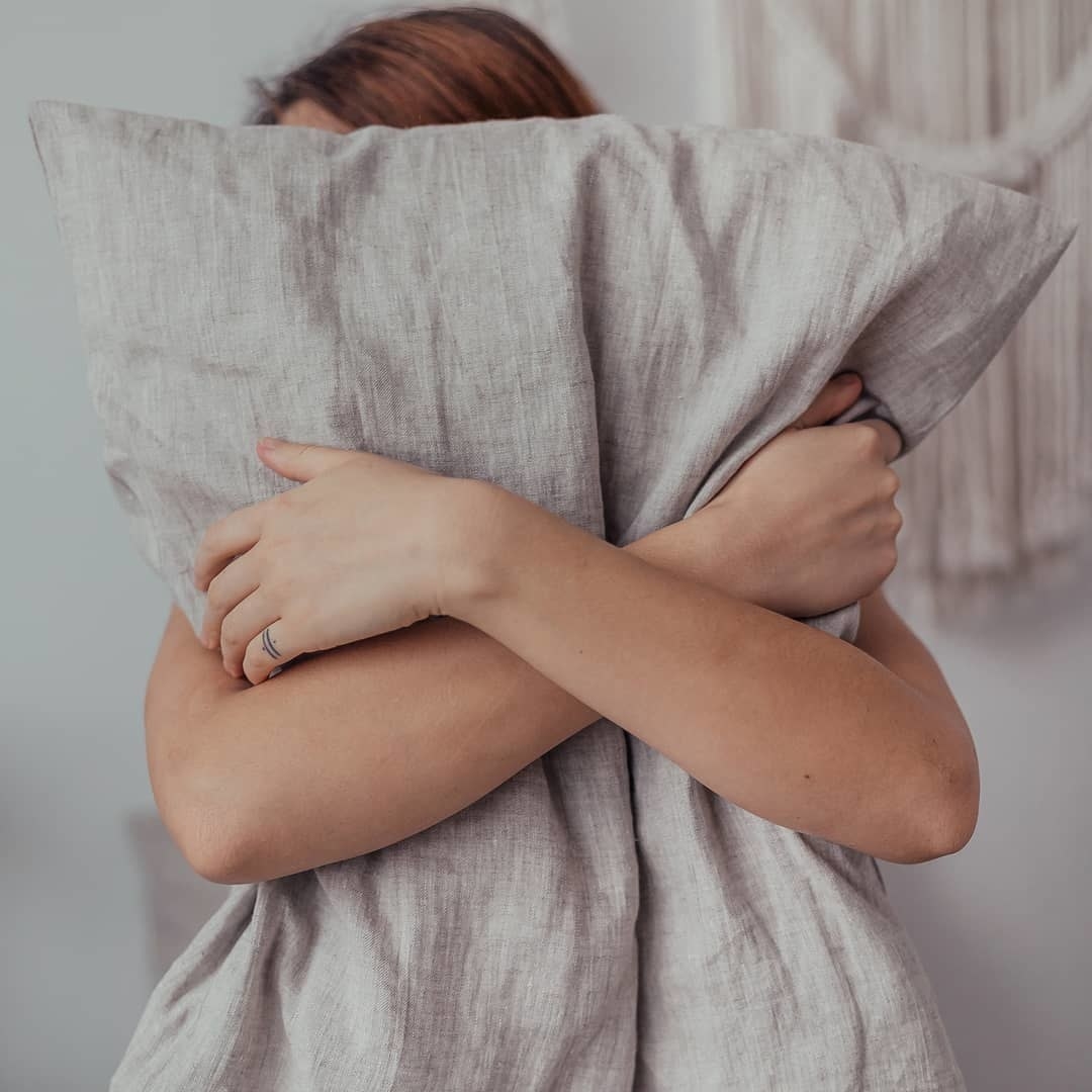 a person cuddling a pillow encased in the crinkly linen pillowcase