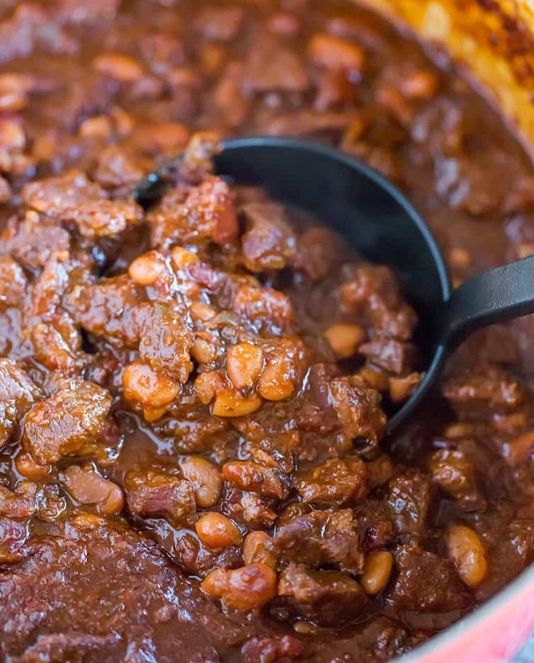 Chili Con Carne in a dutch oven being scooped by a ladle