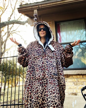 a reviewer wearing the leopard hoodie blanket outdoors