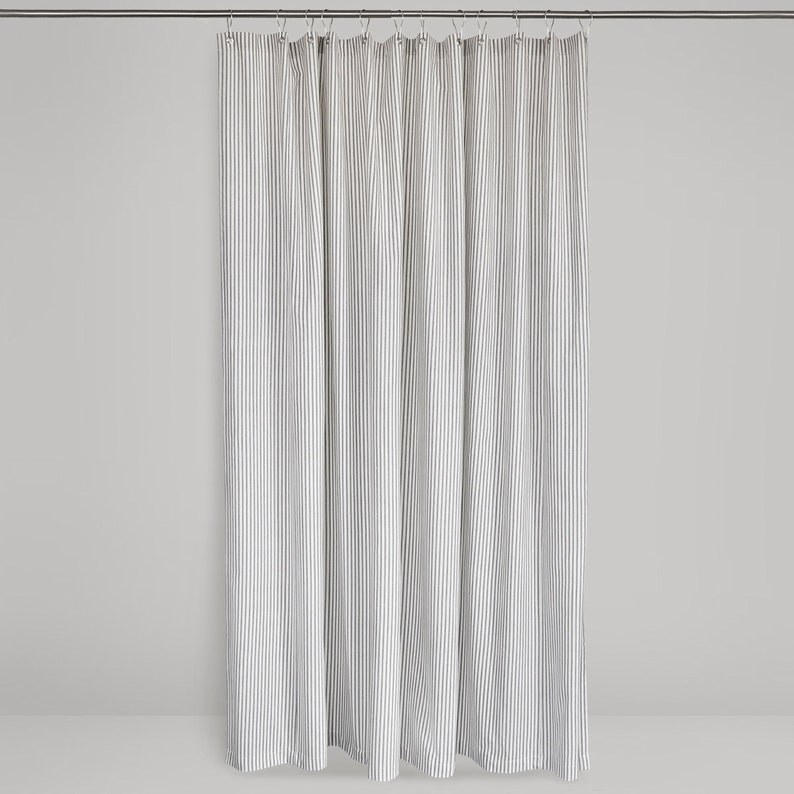 A white and grey vertical striped fabric shower curtain