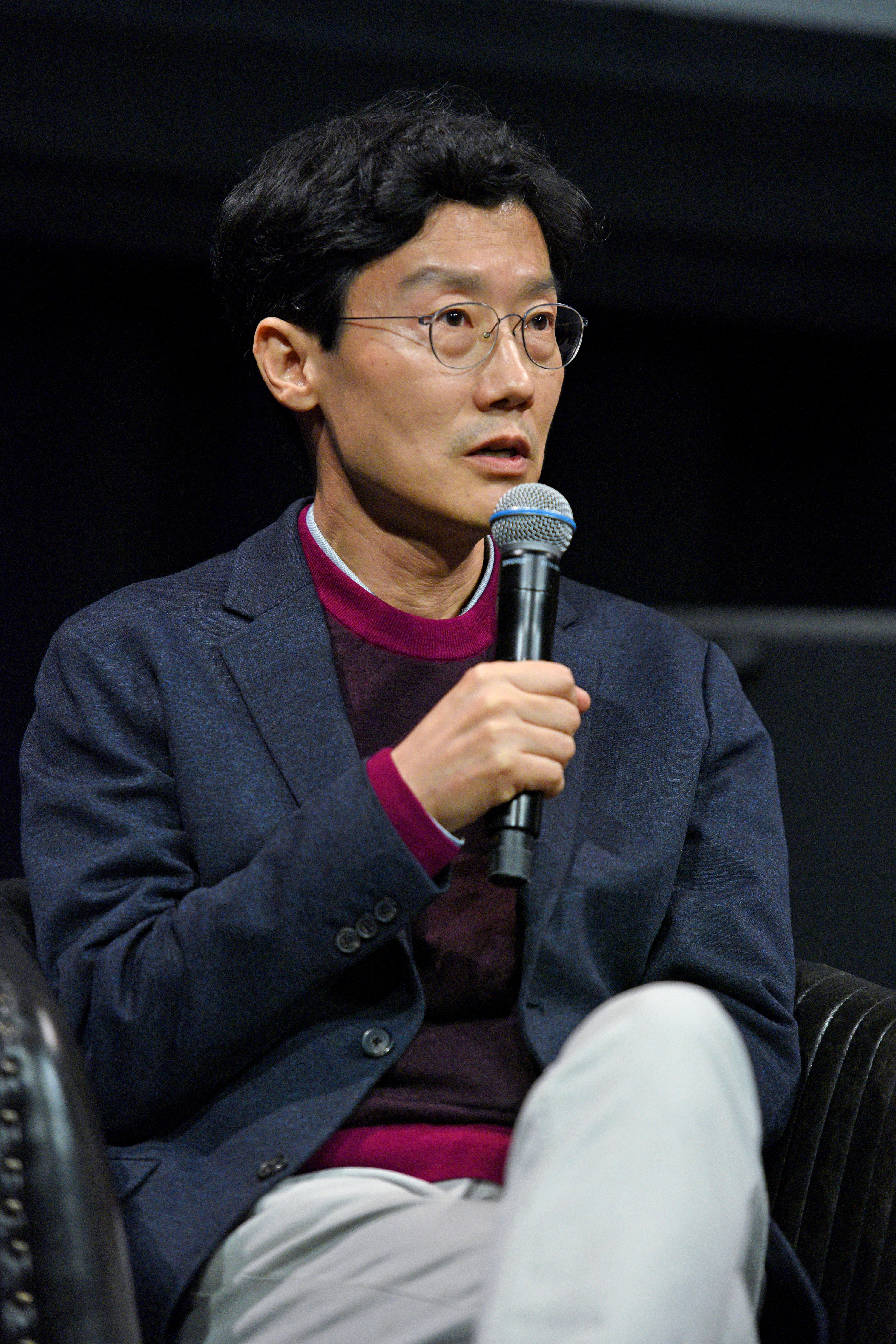 Hwang Dong-hyuk speaking onstage during an interview