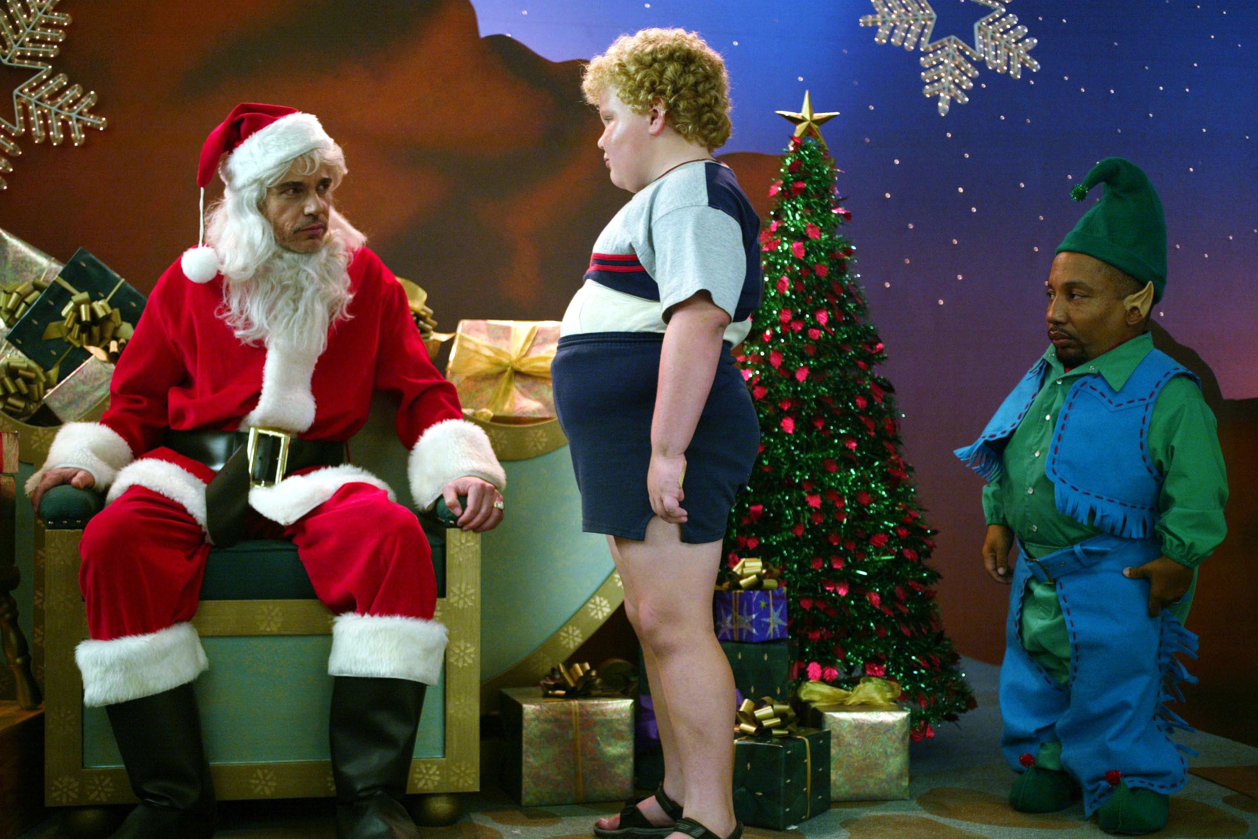Brett Kelly gets ready to sit on Billy Bob Thornton&#x27;s (Santa) lap while Tony Cox looks on as an elf