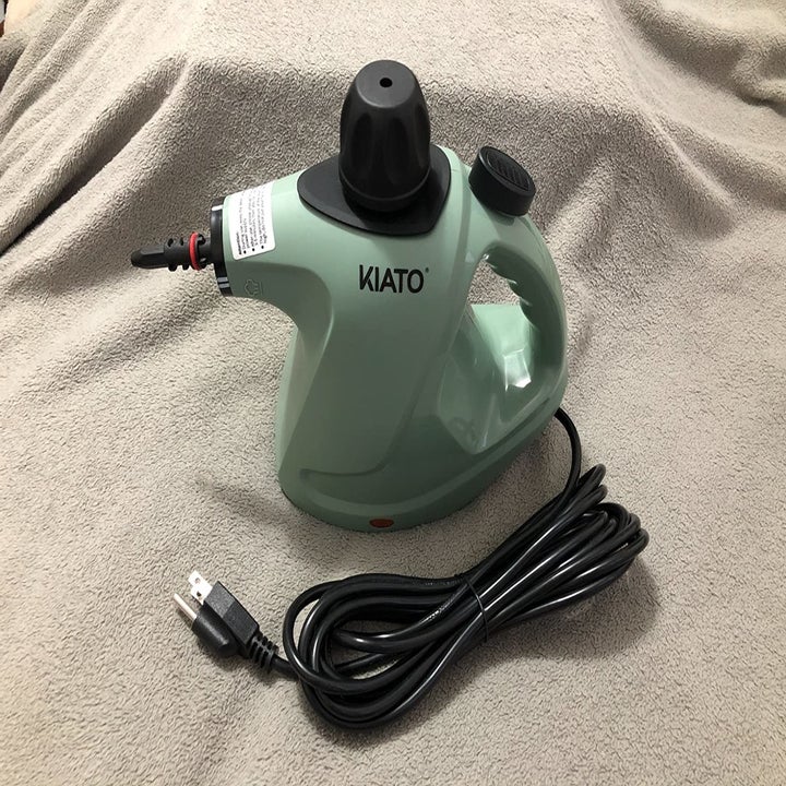 reviewer photo of green handheld steam cleaner and cord/plug