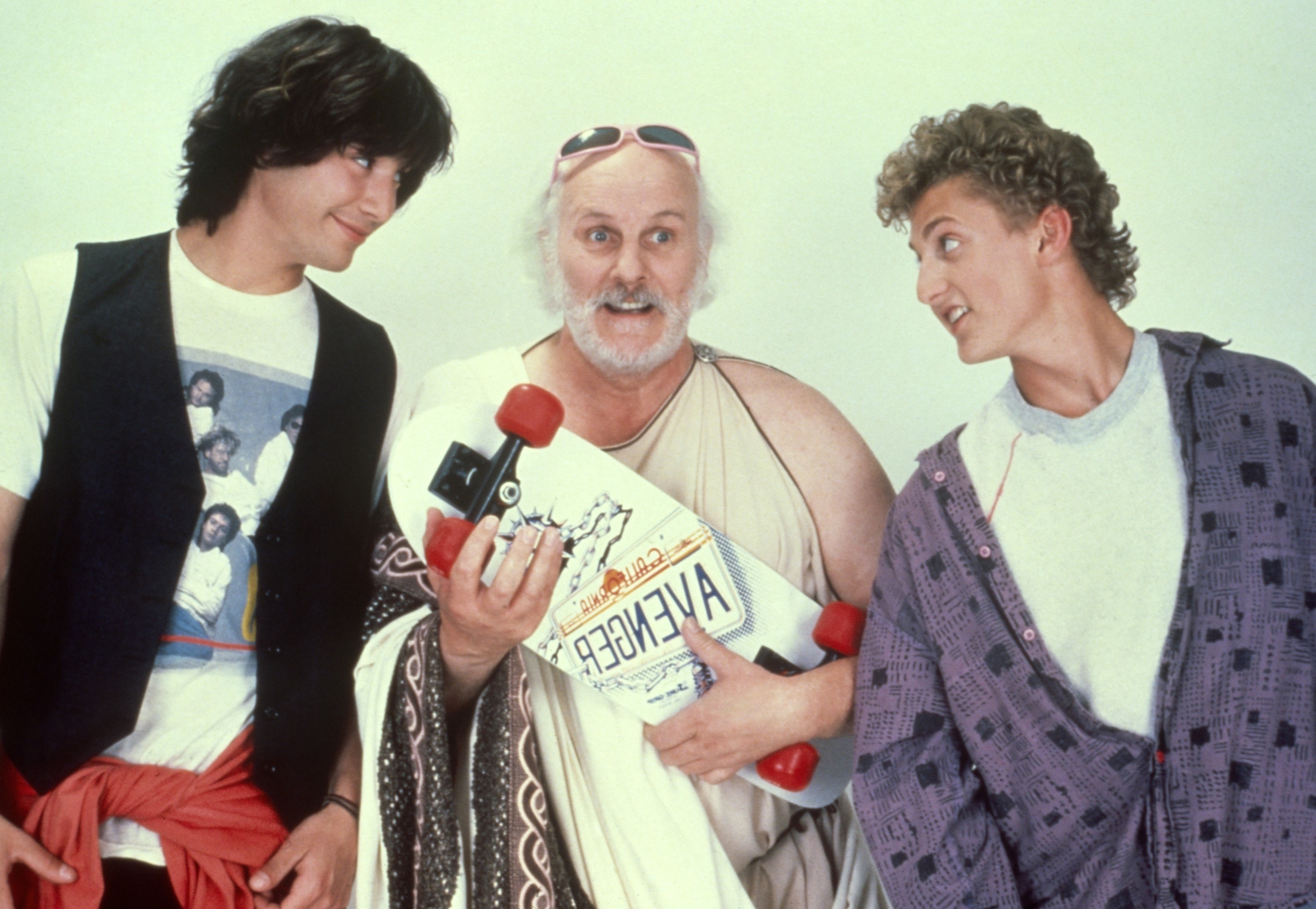 Keanu Reeves and Alex Winter pose with Tony Steedman holding a skateboard