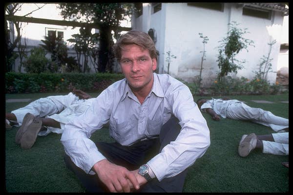 Patrick sitting on the ground cross-legged with people lying around him sexiest man alive