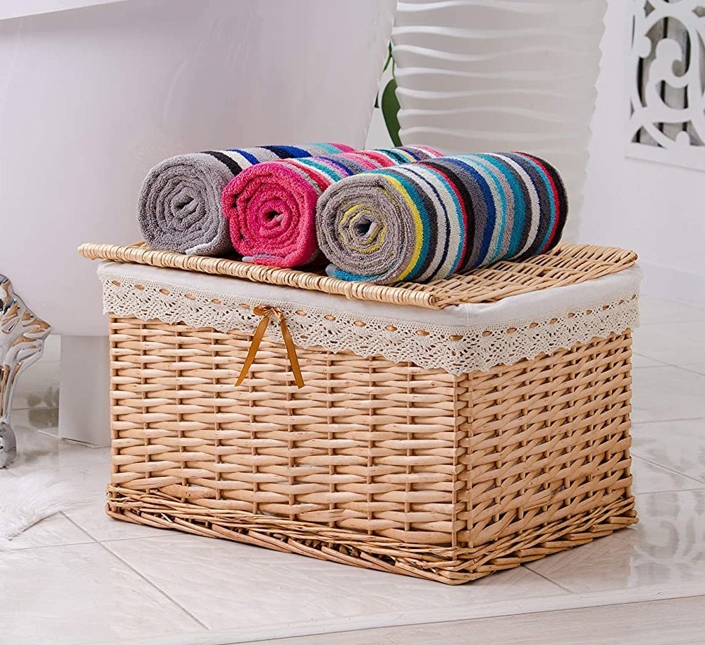 The striped towels rolled up on top of a storage basket in a bathroom