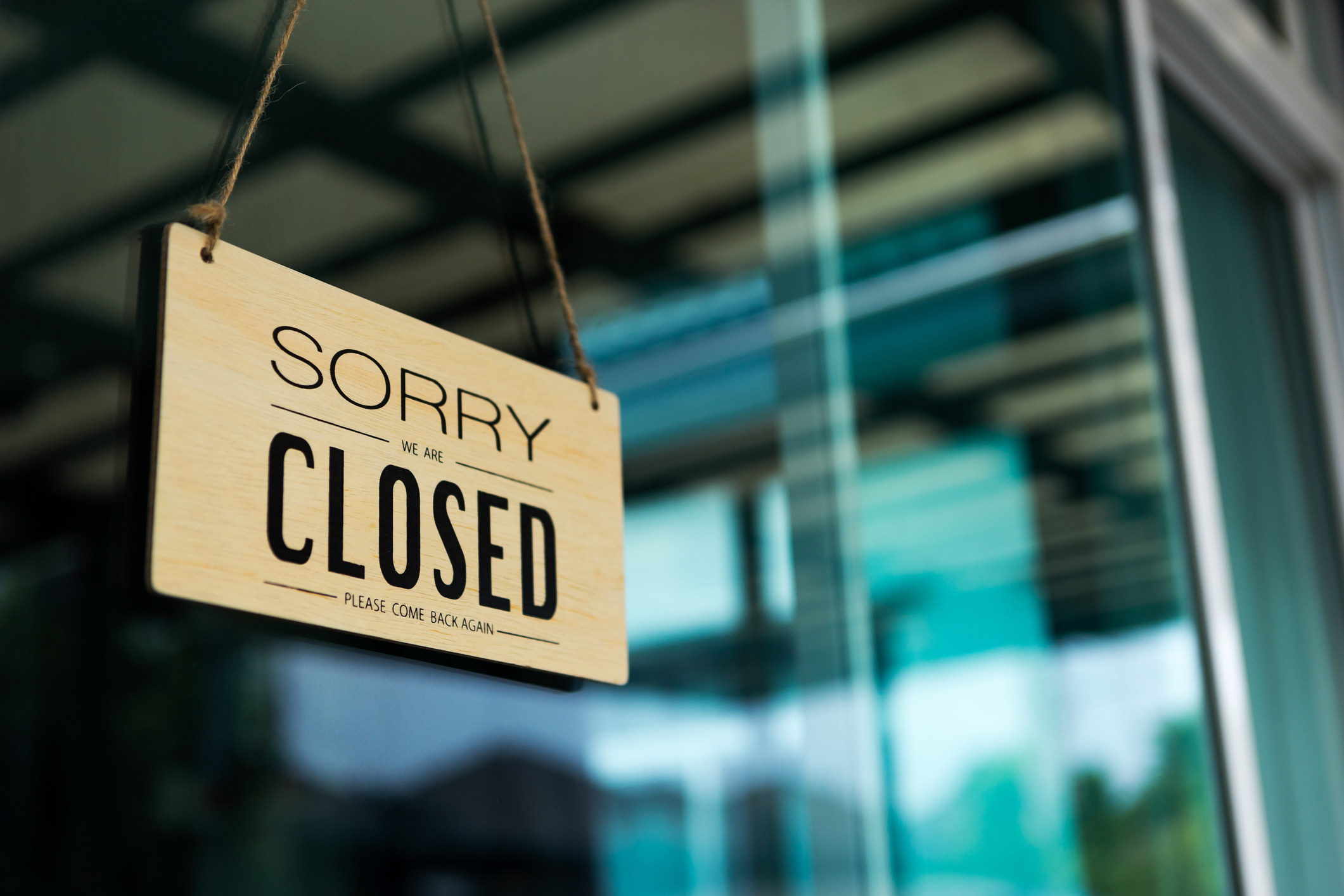 A &quot;we&#x27;re closed&quot; sign hung on a store front