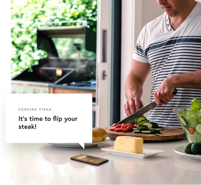 A person getting a notification on his phone telling him to flip his steak.