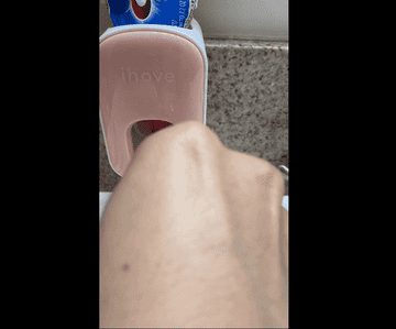 Reviewer GIF showing someone using the pink toothpaste dispenser to put toothpaste on a toothbrush
