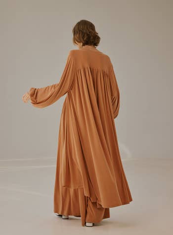 the same model shows the back angle of the cardigan, it has layered look and goes all the down to their ankle