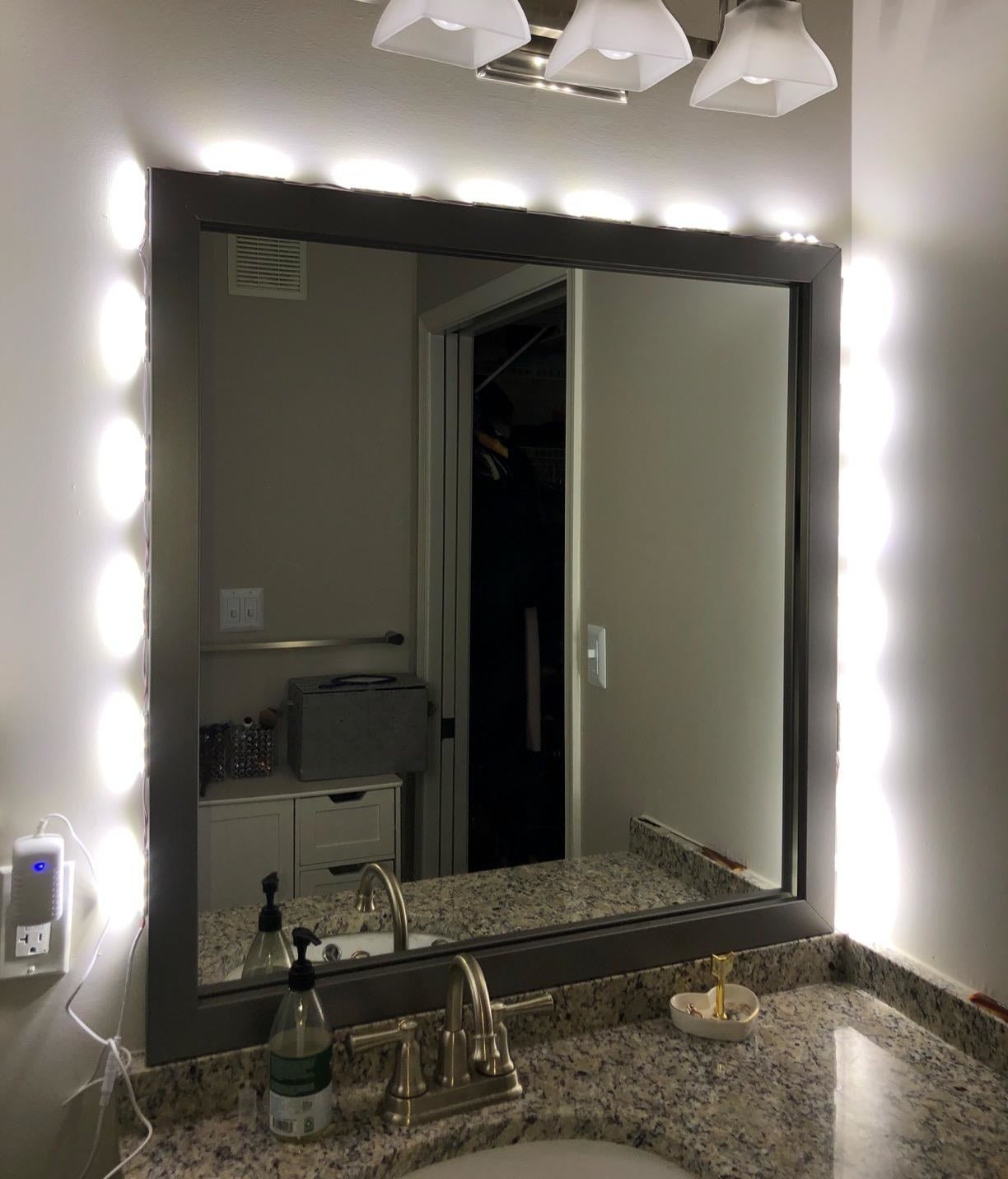 Reviewer photo of the vanity lights lit up around a bathroom mirror
