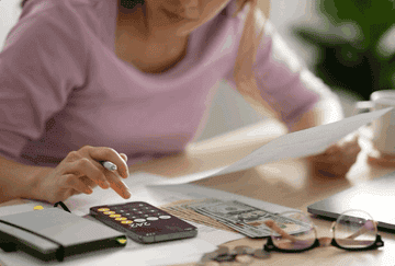 A GIF of a woman using the calculator on her cellphone while holding a piece of paper.