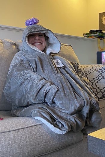 reviewer wearing the comfy in gray while sitting on a couch