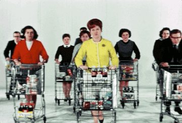 A vintage GIF of women and men pushing shopping carts towards the camera on a white background and white floor.