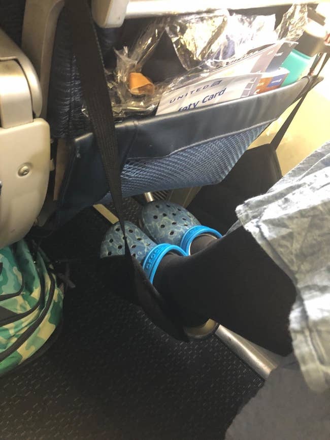 reviewer on a plane, with feet in the sling-like flexible foam footrest