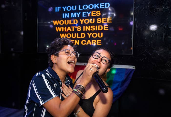 A pair of smiling people sing karaoke
