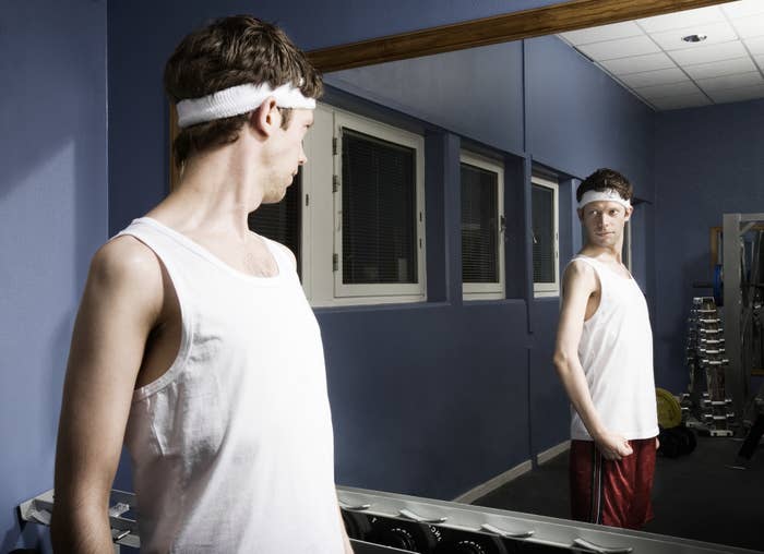 A thin man looking into a gym mirror