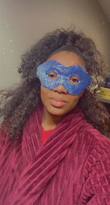 Reviewer uses blue eye mask with eye holes while relaxing in a robe