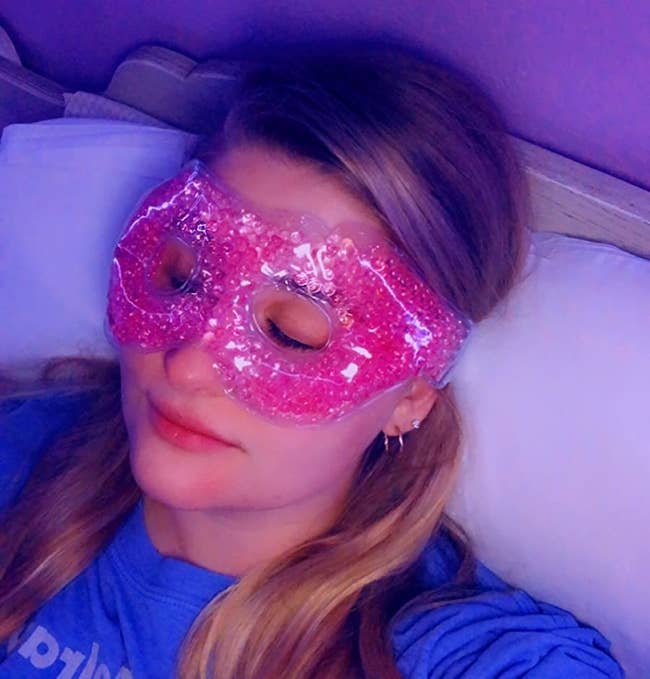 person laying down with their eyes closed while wearing the pink eye mask