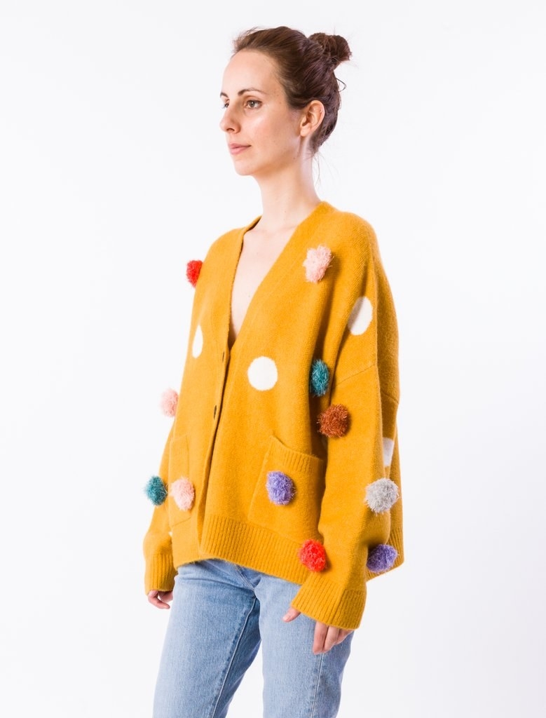 yellow sweater with white polka dots and different colors of pompoms attached to the front
