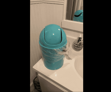 GIF of reviewer tapping the lid of the blue wastebasket, which is on a bathroom countertop