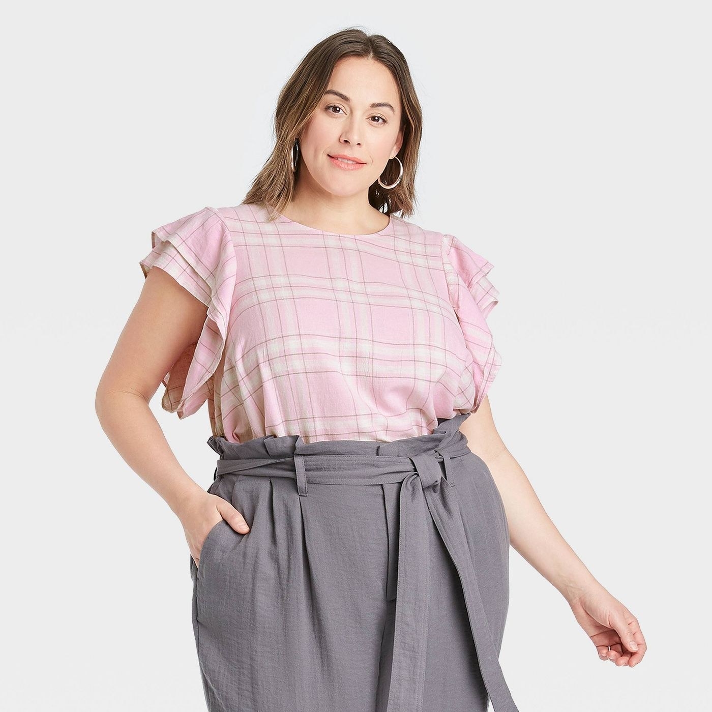 a model wearing the pink plaid top and gray pants