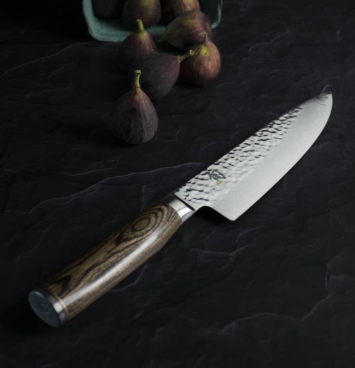 A Shun knife on a black marble table.