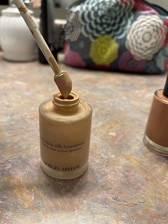 reviewer taking the spatty daddy scooping foundation out of the bottom of a near-empty container