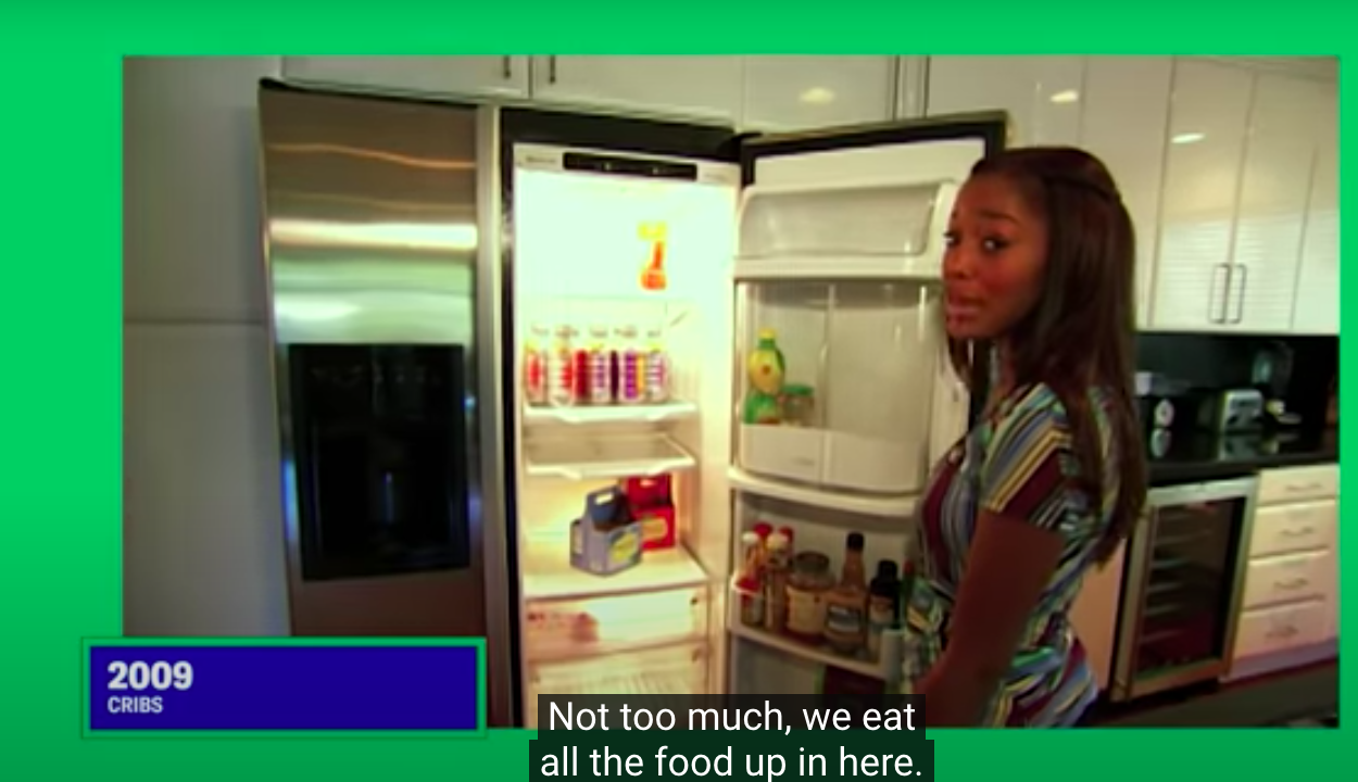 Keke standing holding the door to her half-empty fridge open and saying &quot;Not too much, we eat all the food up in here&quot;