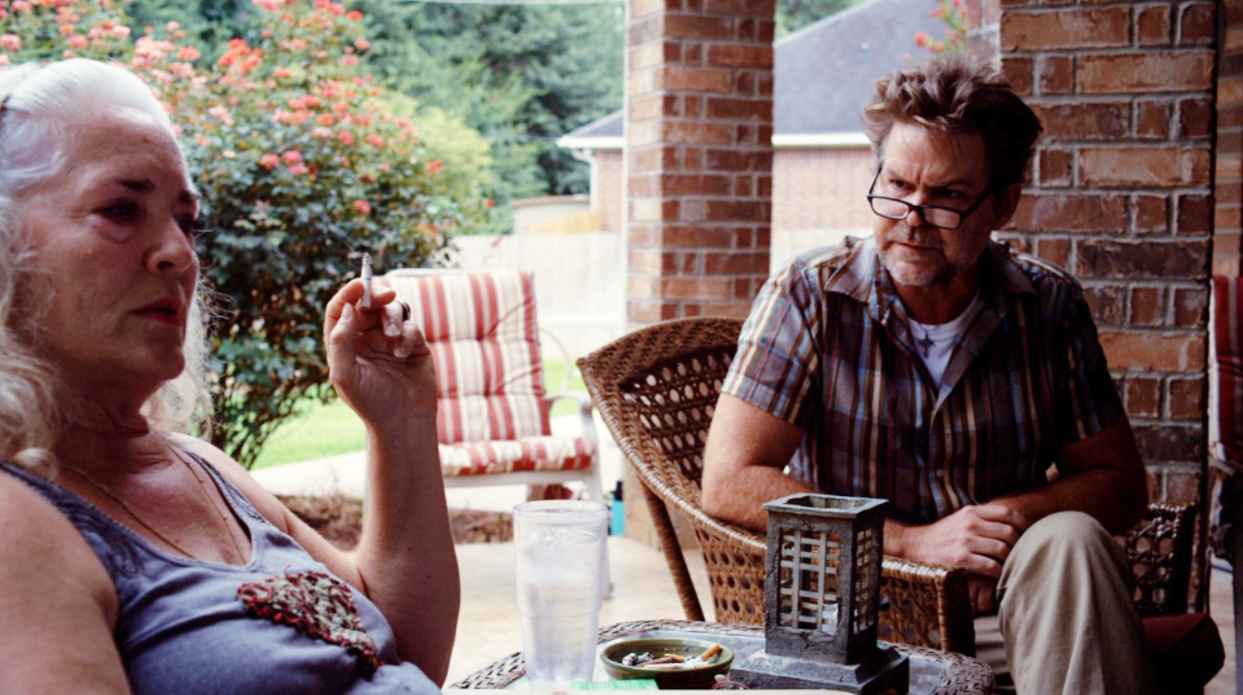 Krisha Fairchild smoking while Bill Wise looks at her.