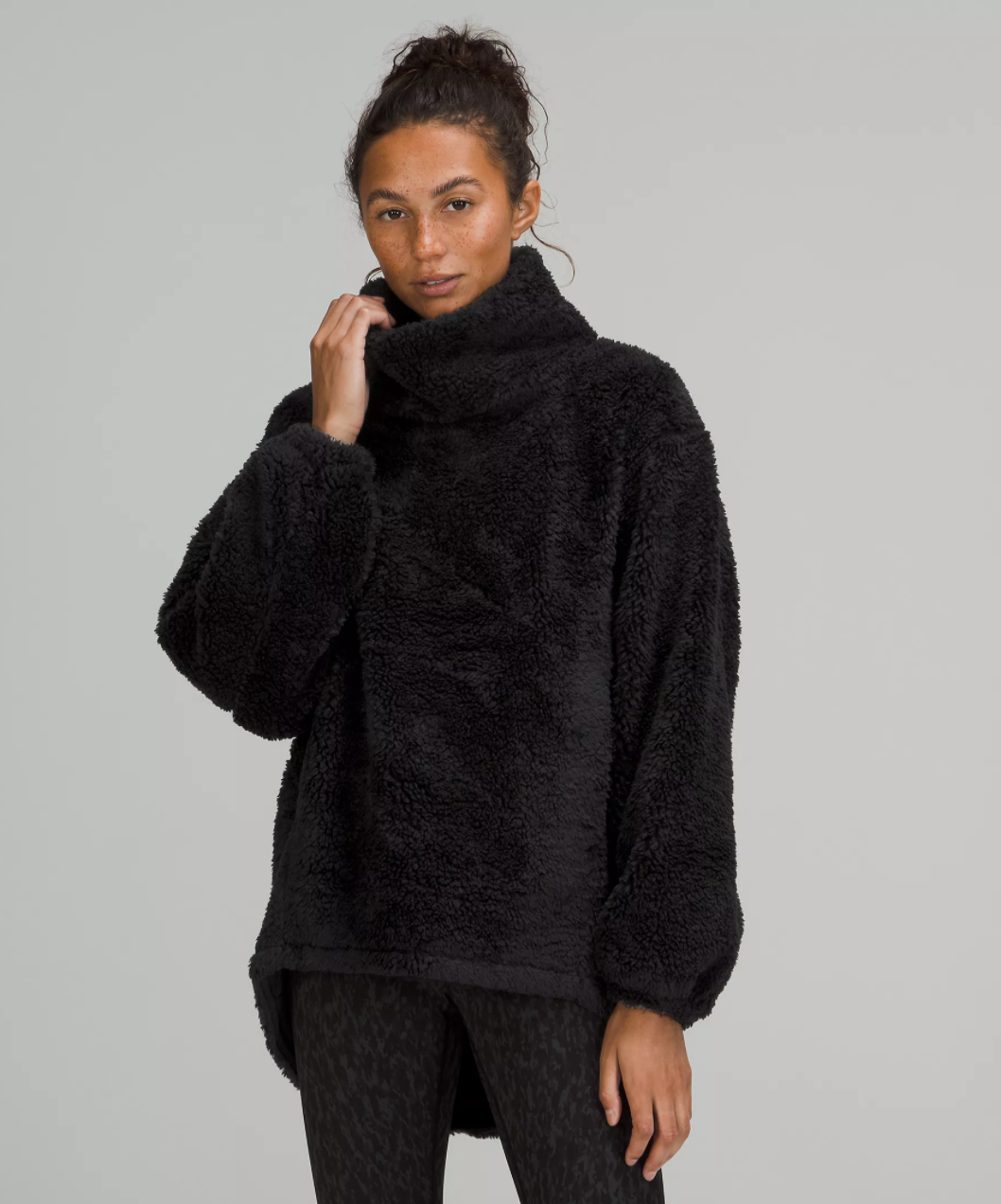 a person wearing the oversized fleece sweatshirt and pulling the oversized collar around their face