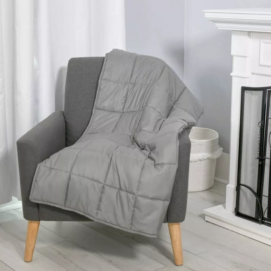 A grey weighted blanket draped on an accent chair