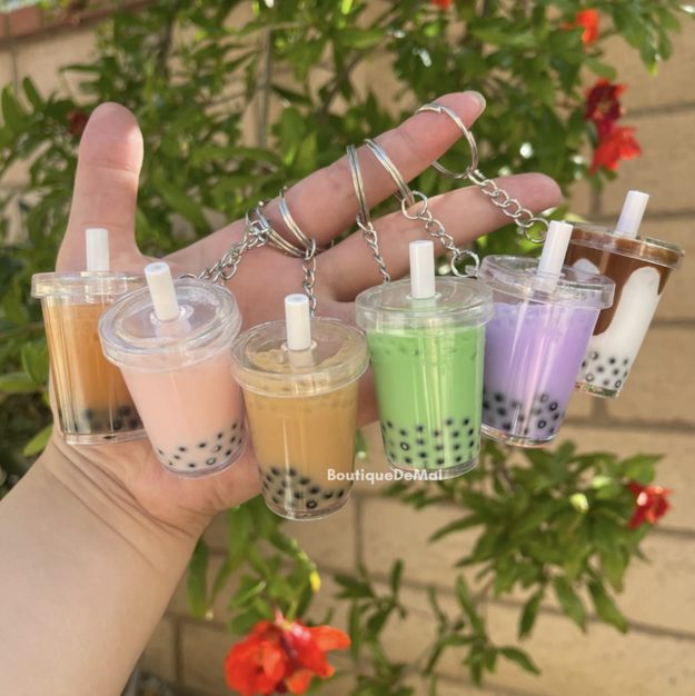 Hand holding various mini boba cup keychains
